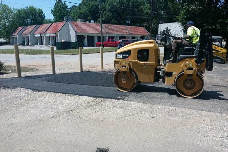 Roller compacting a freshly placed asphalt overlay next to an older grey pavement surface