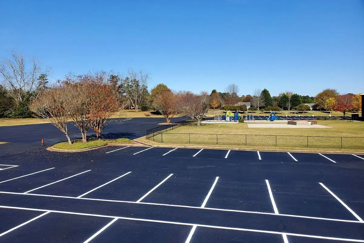 Wide commercial parking lot with freshly painted white stall lines laid out in long rows